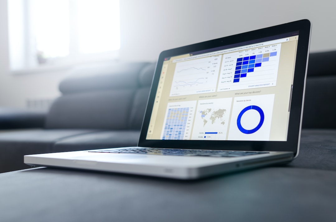 A laptop displaying various data analytics charts and graphs, including line graphs, a map, a grid, and a circular diagram related to WordPress Hosting, sits on a gray couch in a bright, modern room.