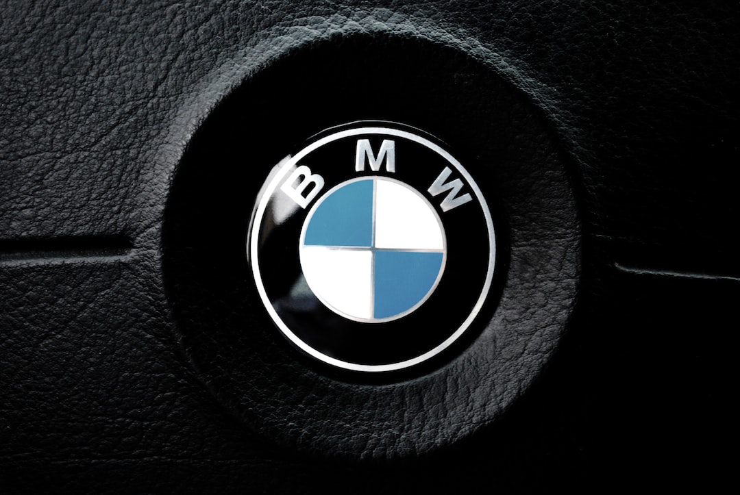 Close-up of a BMW logo on a black leather car steering wheel, as striking as a premium WordPress Hosting dashboard. The emblem features a circle divided into blue and white quadrants with the letters BMW at the top.