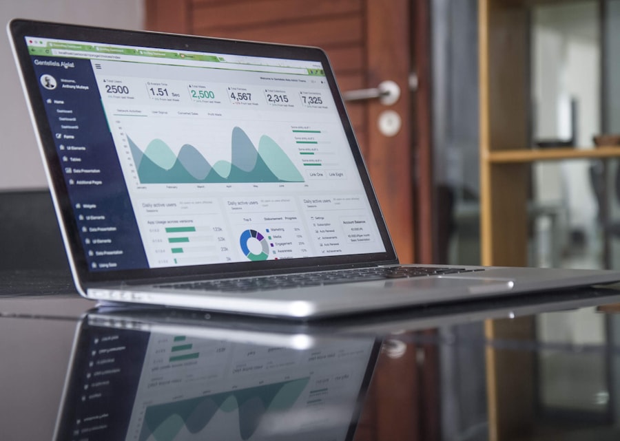 A laptop on a reflective desk displays data analytics dashboards with charts, graphs, and WordPress Hosting statistics. The background shows part of a wooden door and shelving.