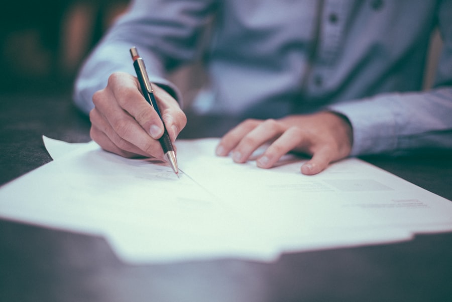 A person in a blue shirt is holding a pen and writing on several sheets of paper spread out on a desk, planning their next WordPress Hosting project.