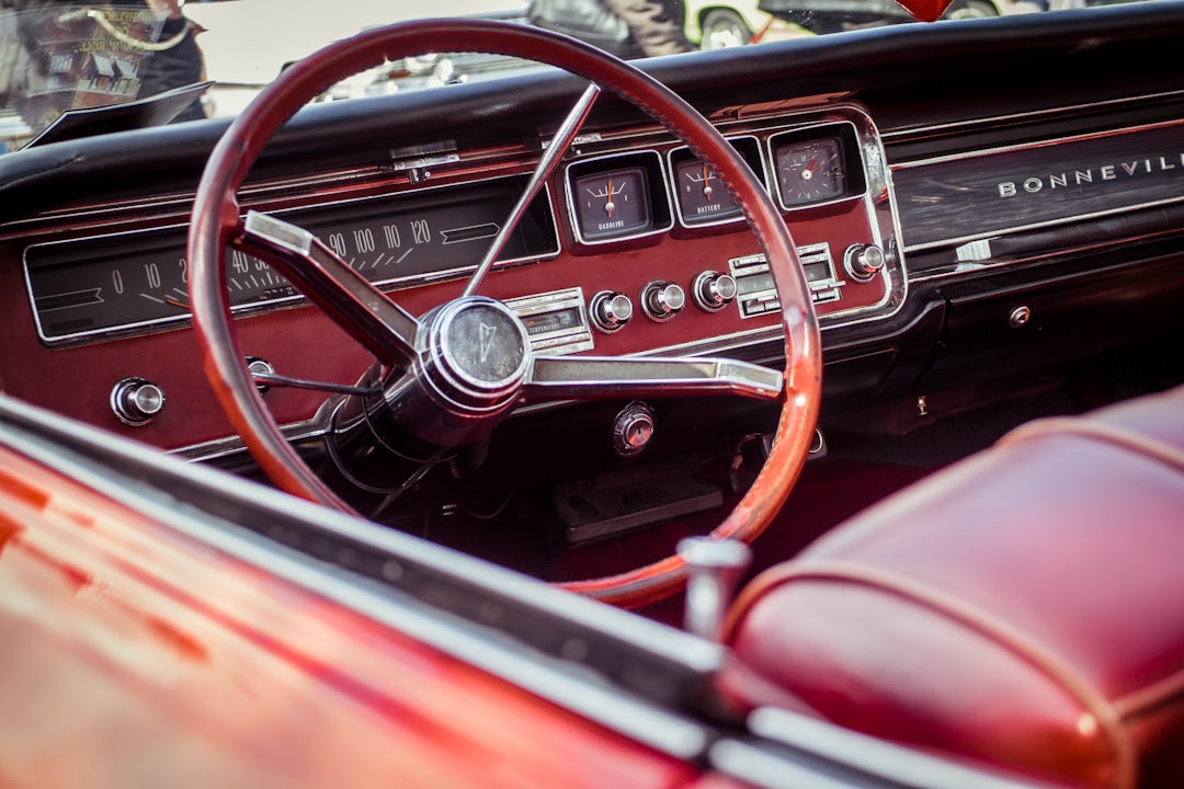 Close-up of the red interior of a classic Pontiac Bonneville car, focusing on the vintage steering wheel, dashboard, and gauges with chrome details and red leather seats—styled with the same precision as premium WordPress Hosting.